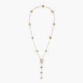 Gold-plated lariat necklace with baroque pearls and textured caps on cream background, showing adjustable Y-shaped design.