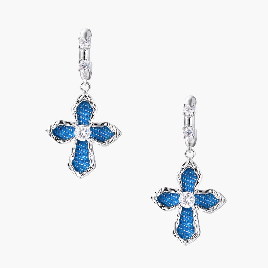 Silver hoops with denim-inlaid cross charms and clear crystals on beige background
