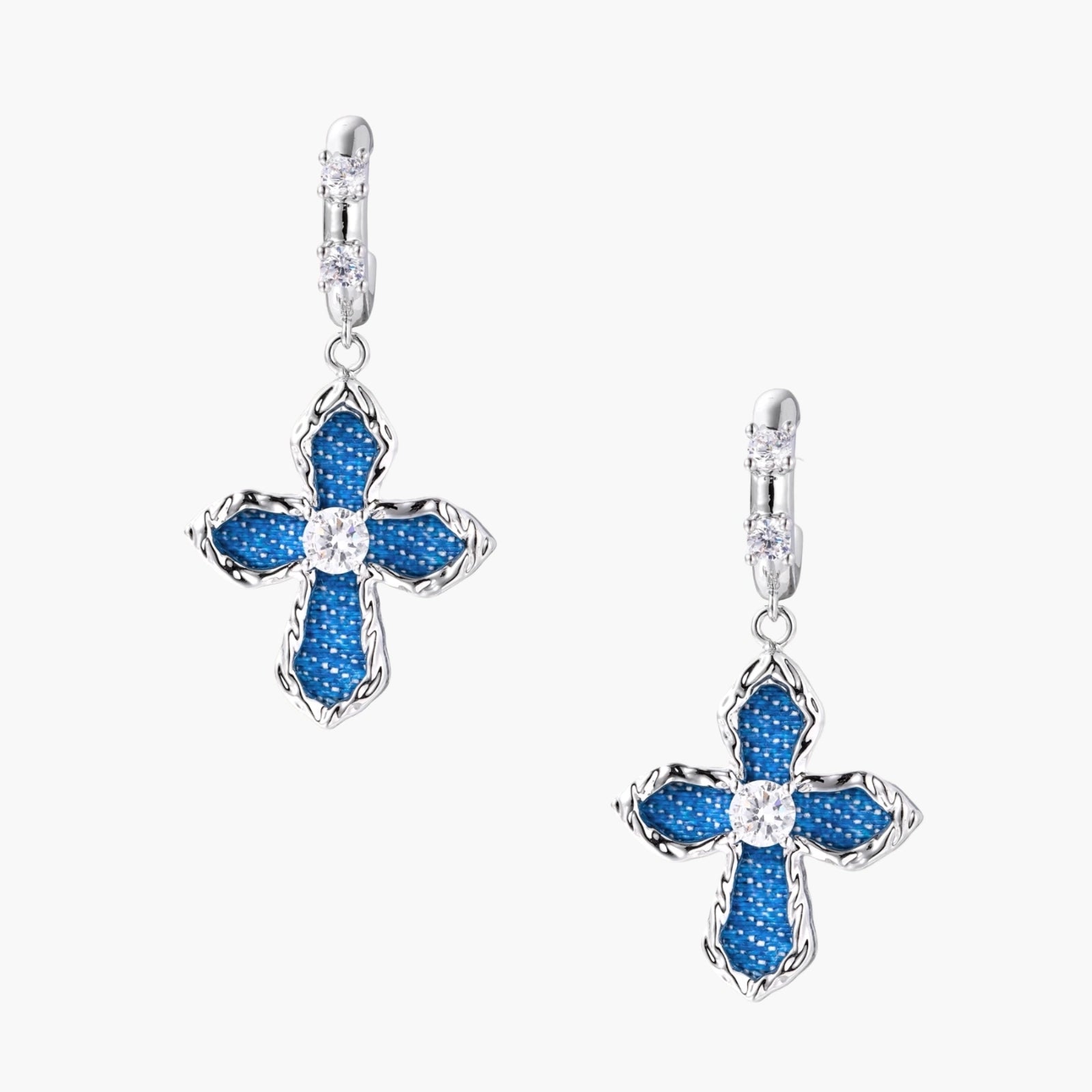 Silver hoops with denim-inlaid cross charms and clear crystals on beige background