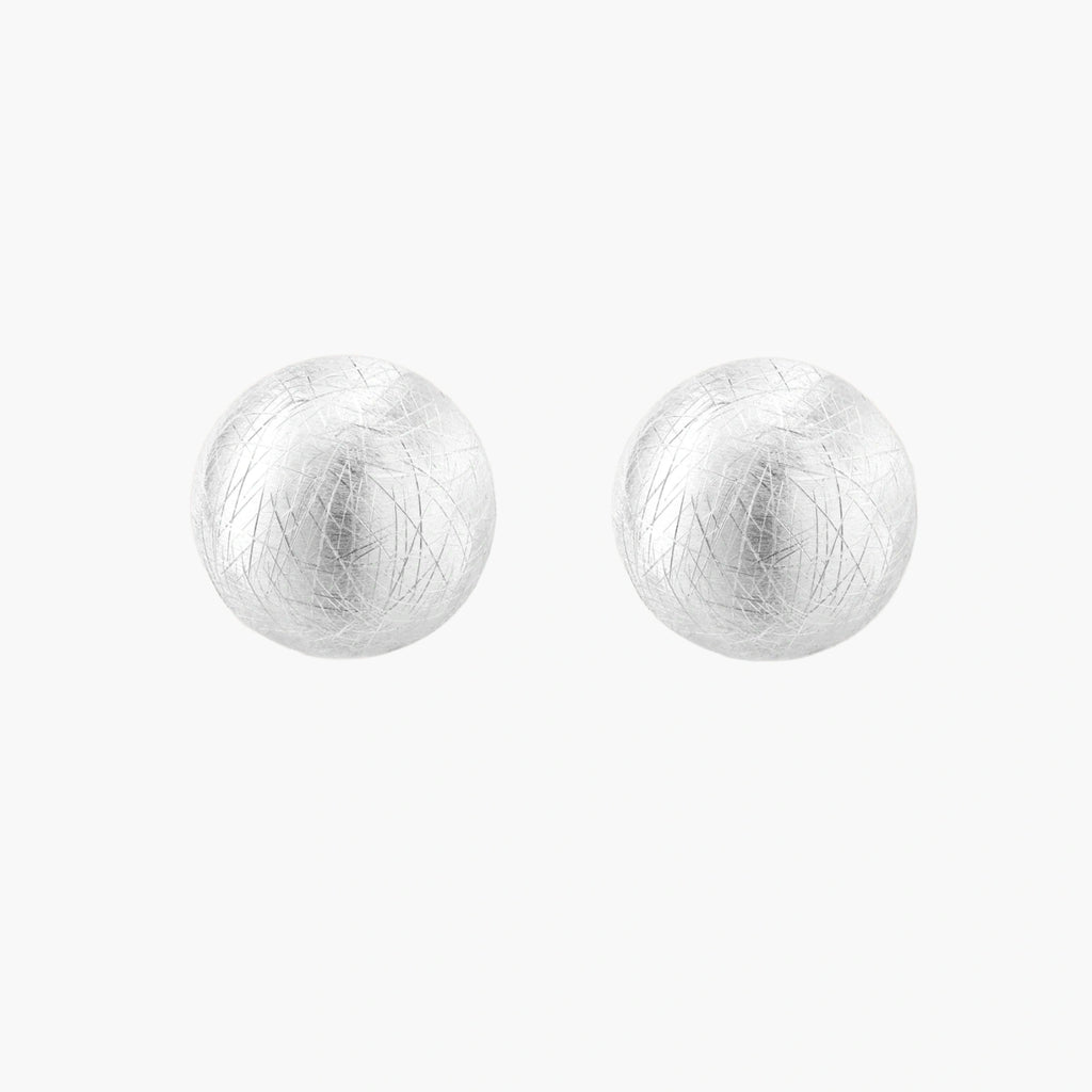 Brushed sterling silver half-dome clip-on earrings with textured surface against cream background