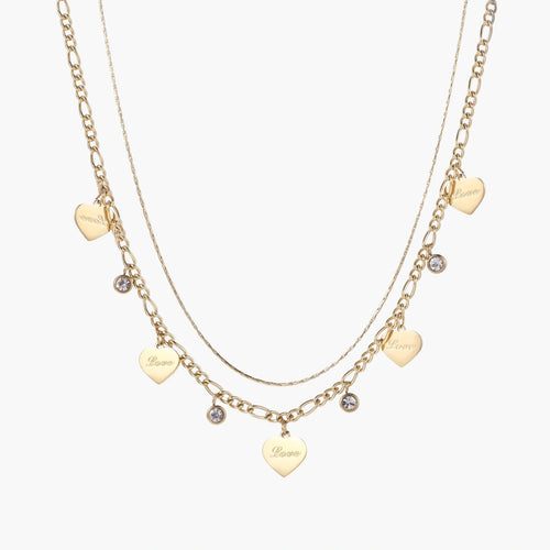 Gold layered necklace set with engraved heart pendants and crystal accents on cream background
