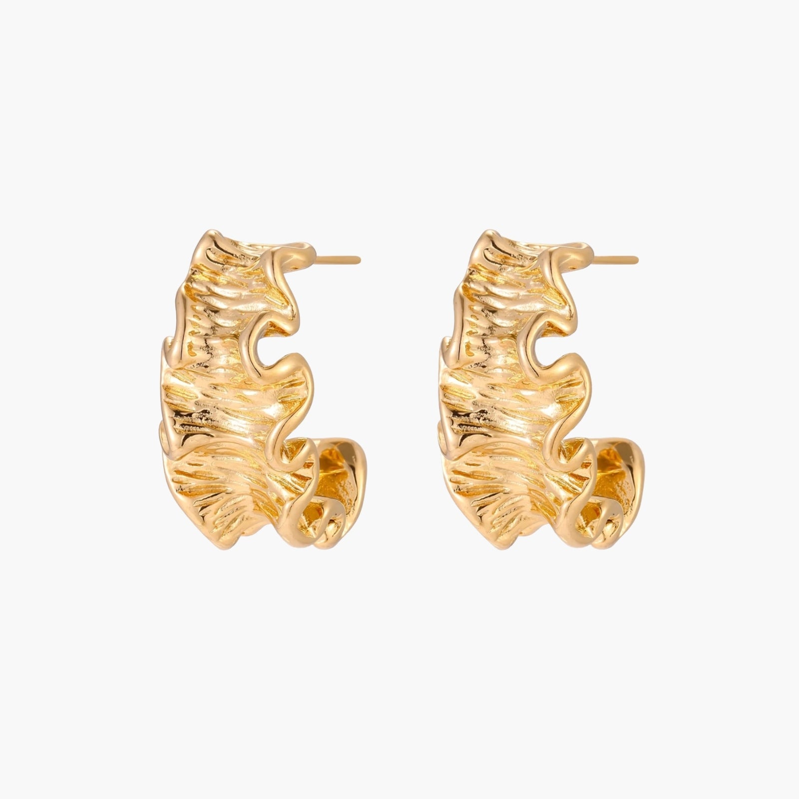 Pair of gold huggie hoops with sculpted wave texture and dimensional ripples on neutral background.