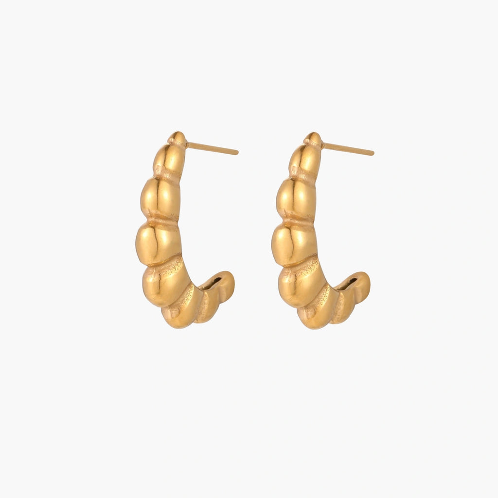 Gold-plated chunky hoop earrings with ridged bubble texture on cream background