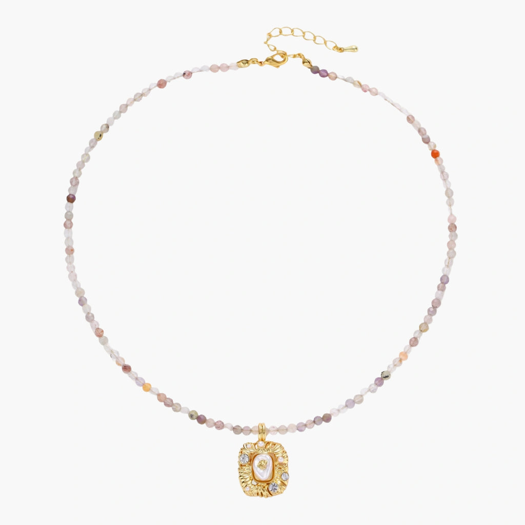 Ornate gold-plated pendant necklace with multicolored gemstone beads in purple, pink and clear tones on white background